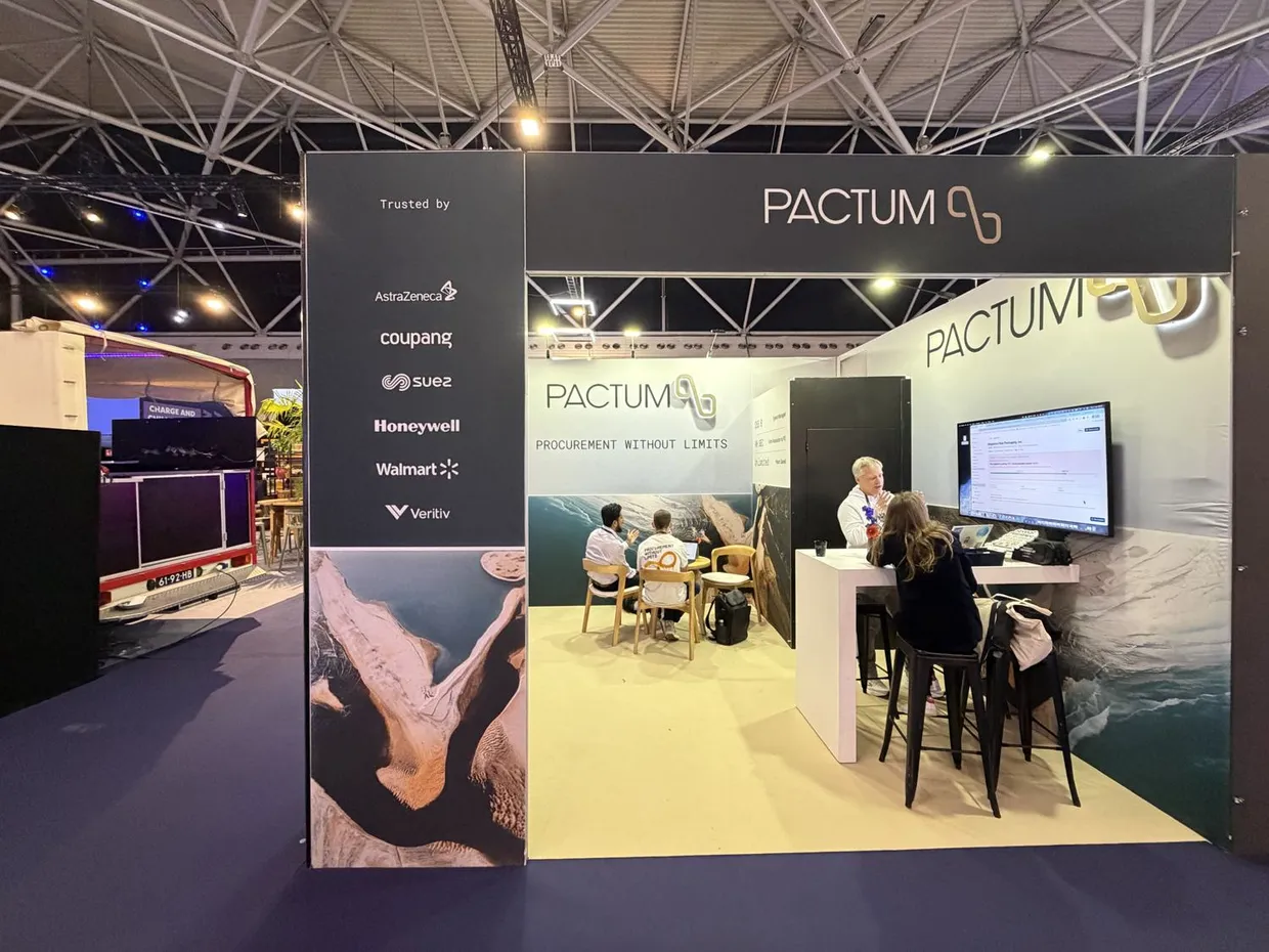 The Pactum stand with a product demo on the main screen and visitors at the table