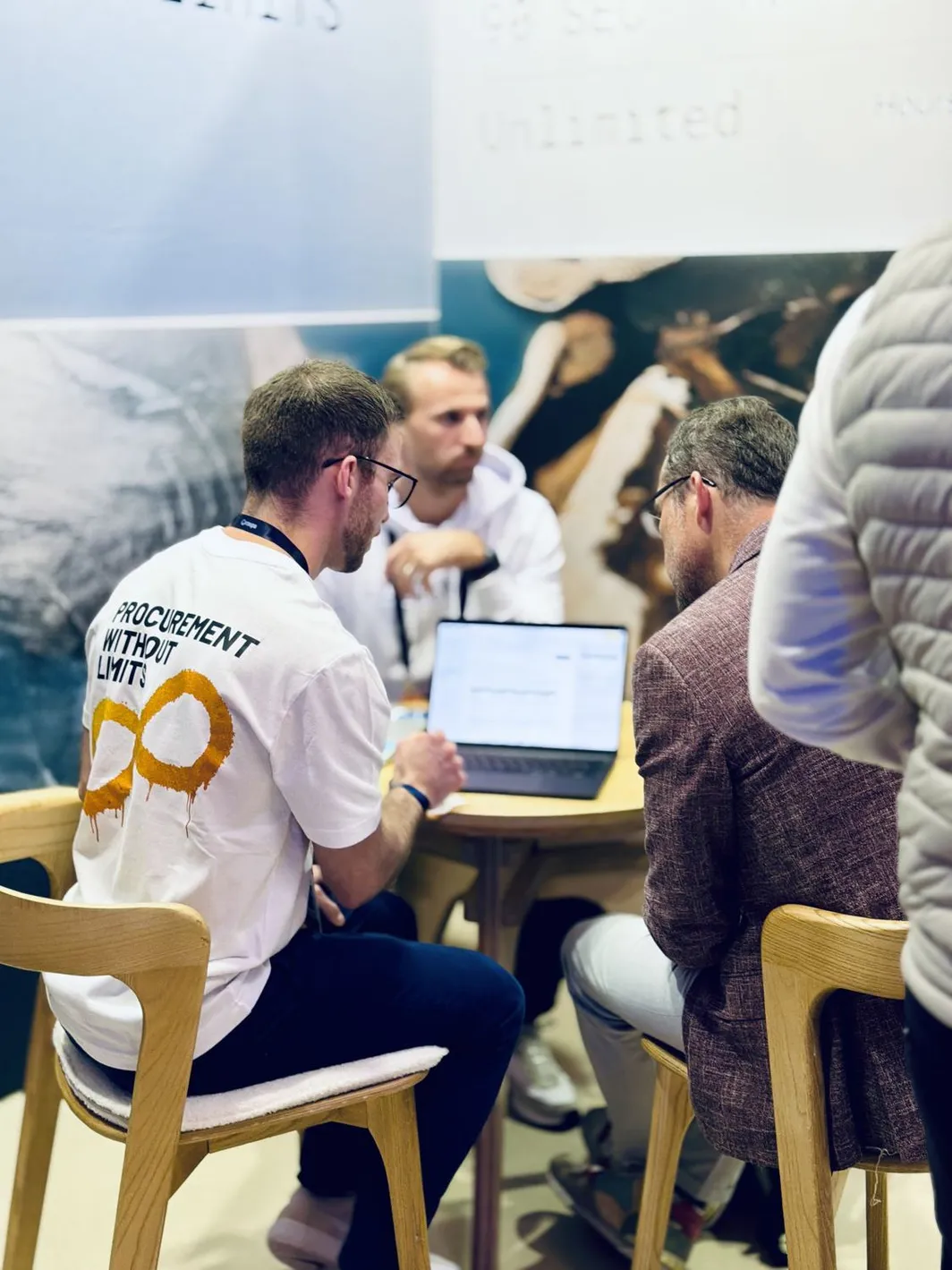 A Pactum team member walking a visitor through the product on a laptop at the stand